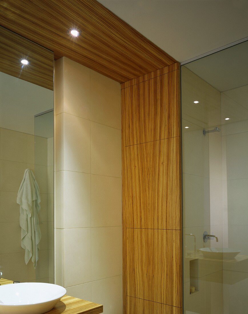 Ausschnitt eines Designerbads mit Waschtisch und umlaufender Holzrahmen an Wand und Decke mit Einbaustrahlern
