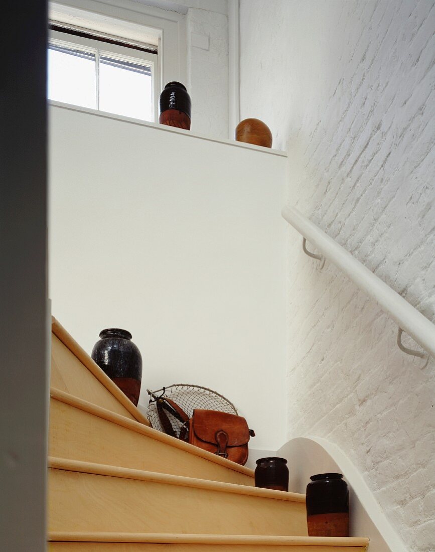 Ausschnitt eines Treppenaufgangs mit Tongefässen auf Holzstufen und geweisselter Ziegelwand