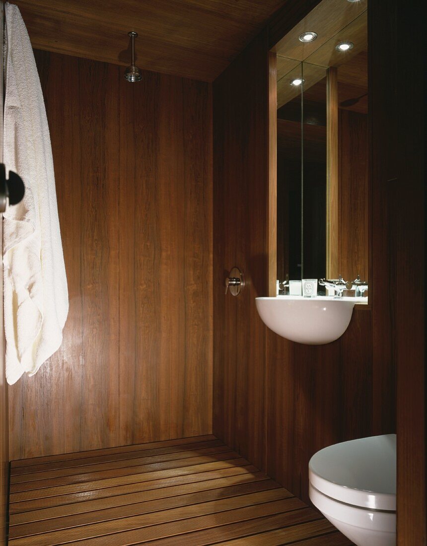 Holzverkleideter Badraum mit Waschbecken und Spiegel in Nische