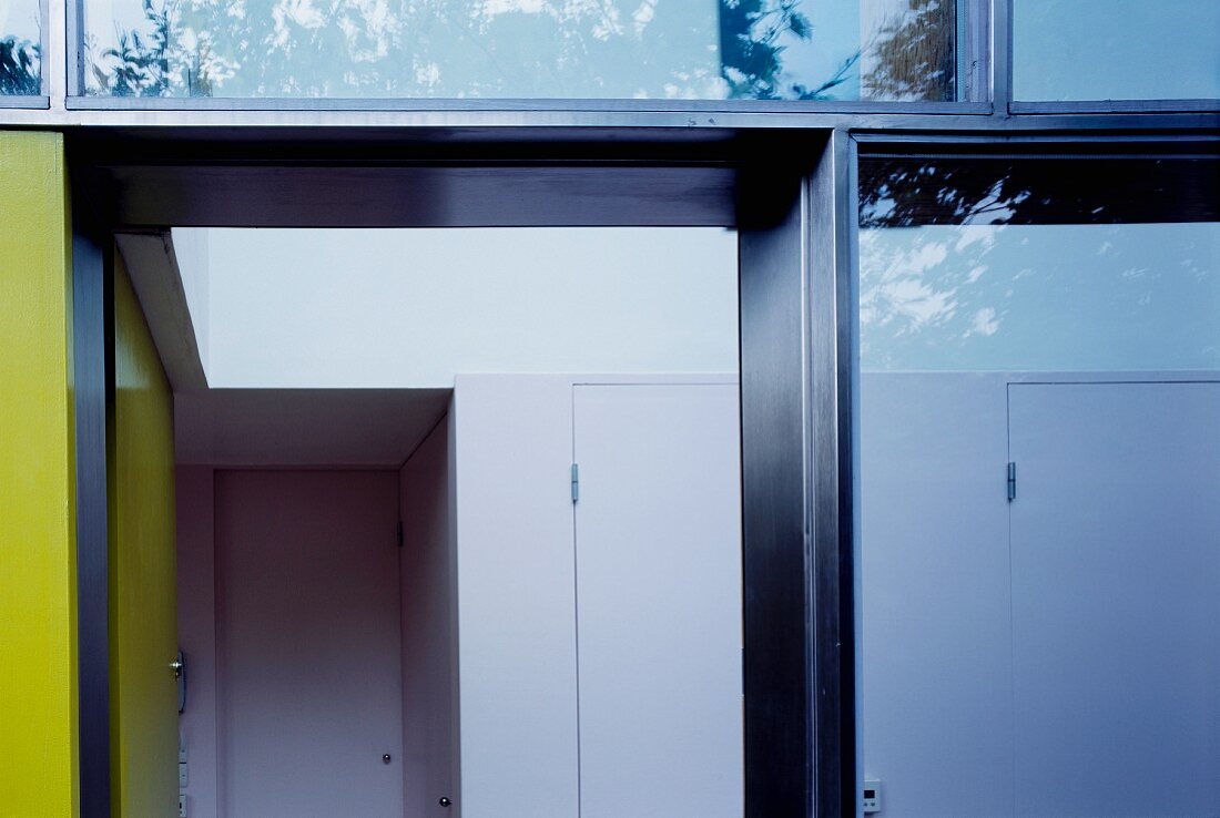 View through a glass facade into a hallway with a built-in wardrobe