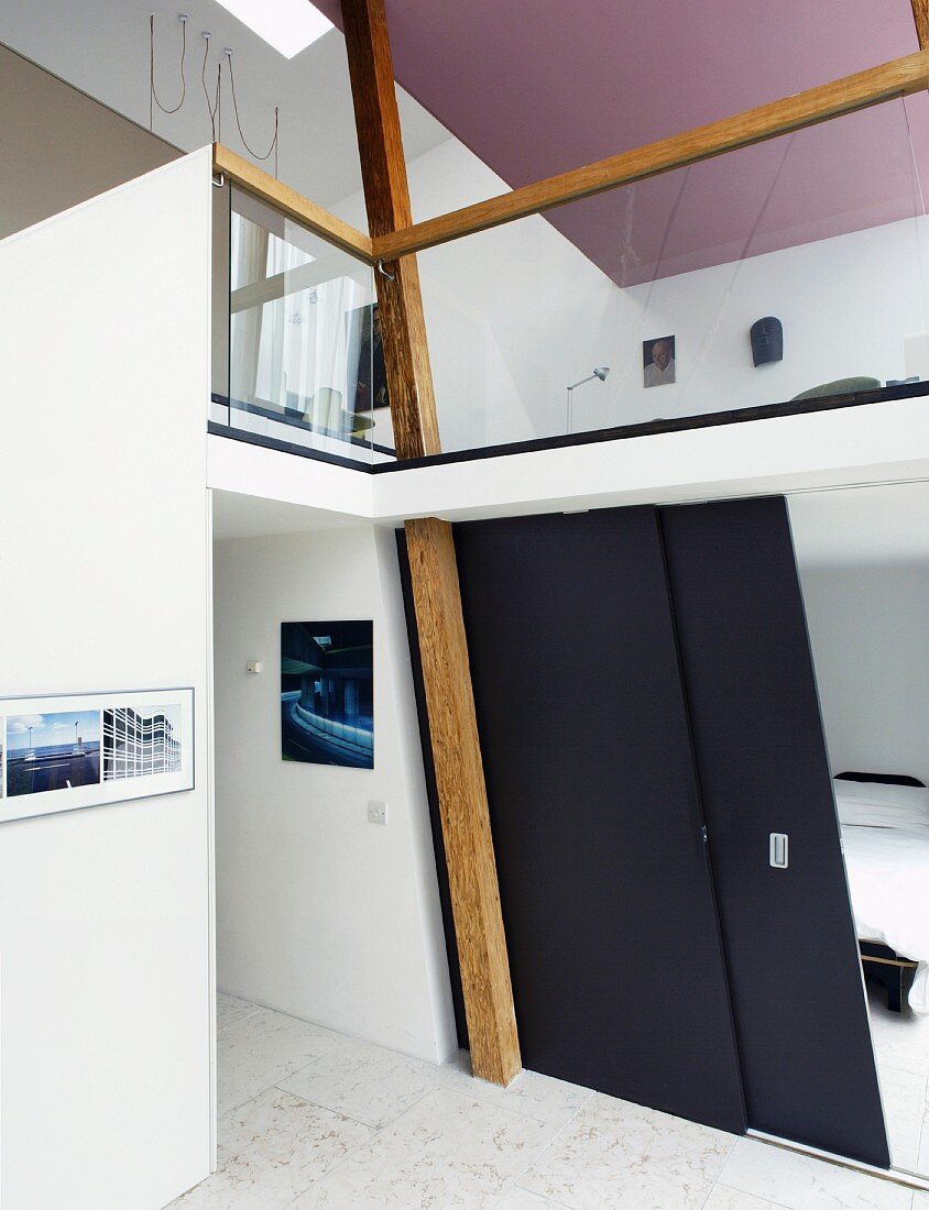 Schwarze Schiebetür im offenem Wohnraum mit Blick auf Galerie und violetter Decke