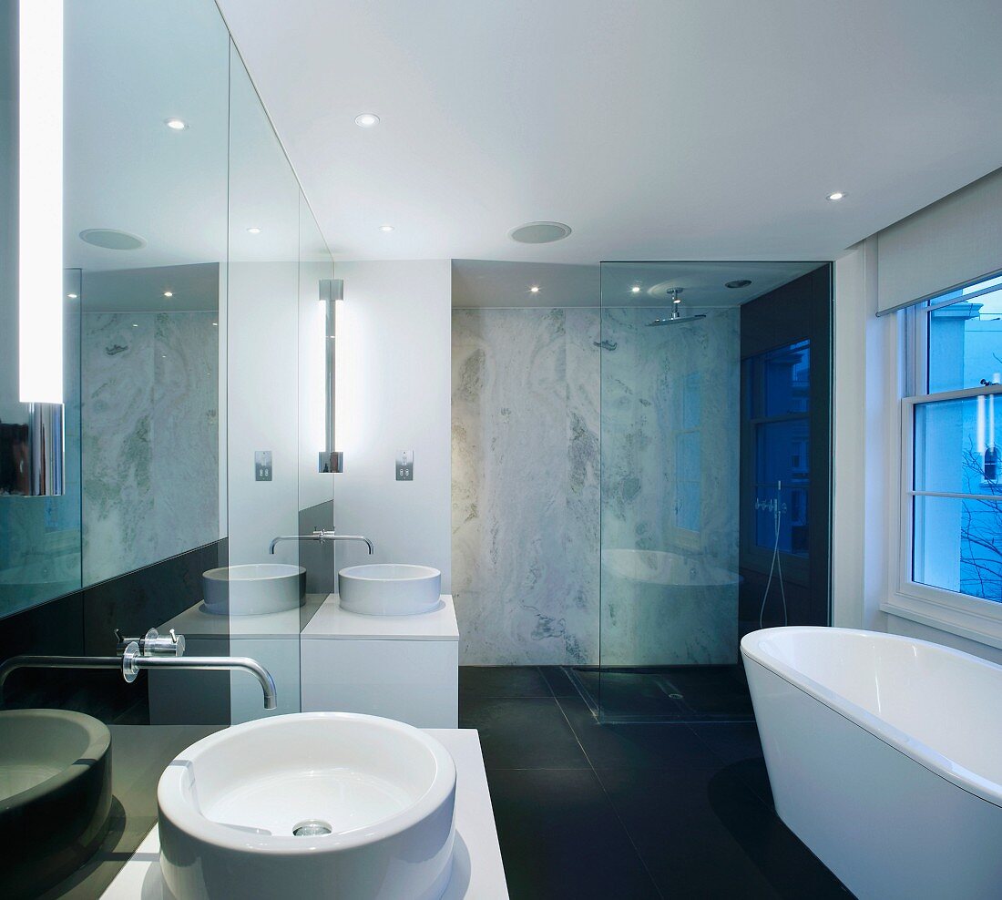 Einzelwaschtische vor verspiegelter Wand im Designerbad mit verglastem Duschbereich