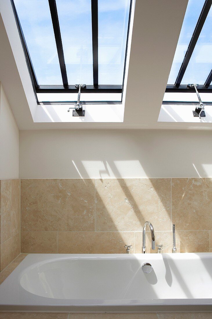 Modern bathroom under a pitched roof with skylights above a bathtub