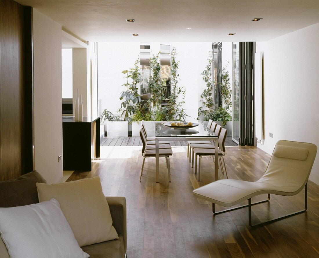 Offener Wohnraum mit weisser Lederliege vor Esstisch mit Stühlen und Terrassenblick