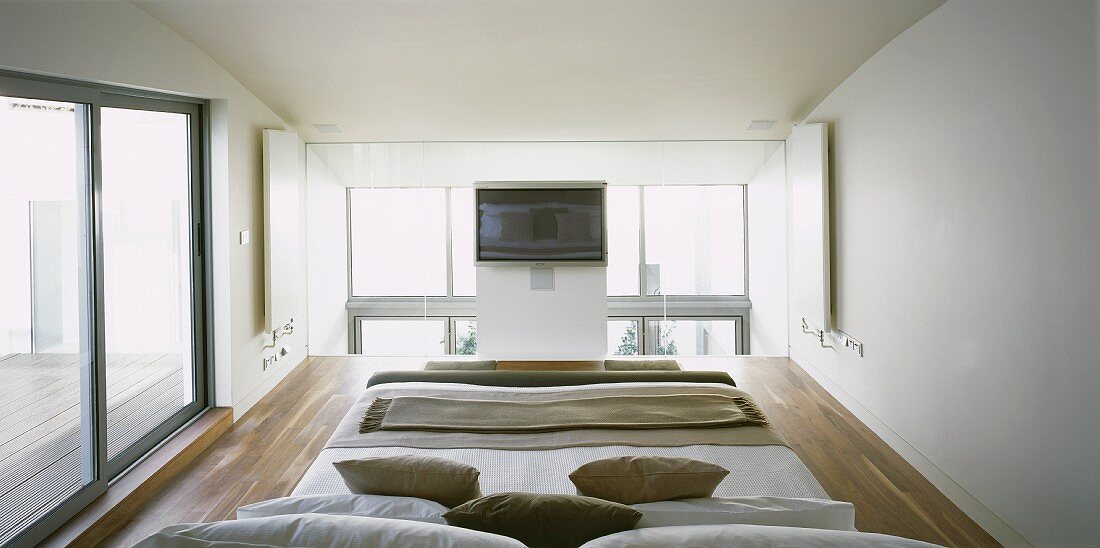 Schlafbereich auf Galerie im modernen Neubauhaus mit Terrassenschiebetüren
