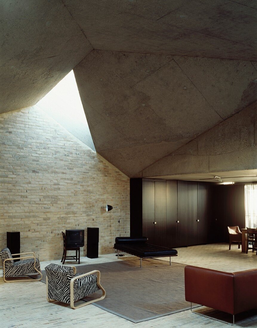 Wohnraum in futuristischer Architektur mit verschiedenen Sitzmöbeln im Stilmix