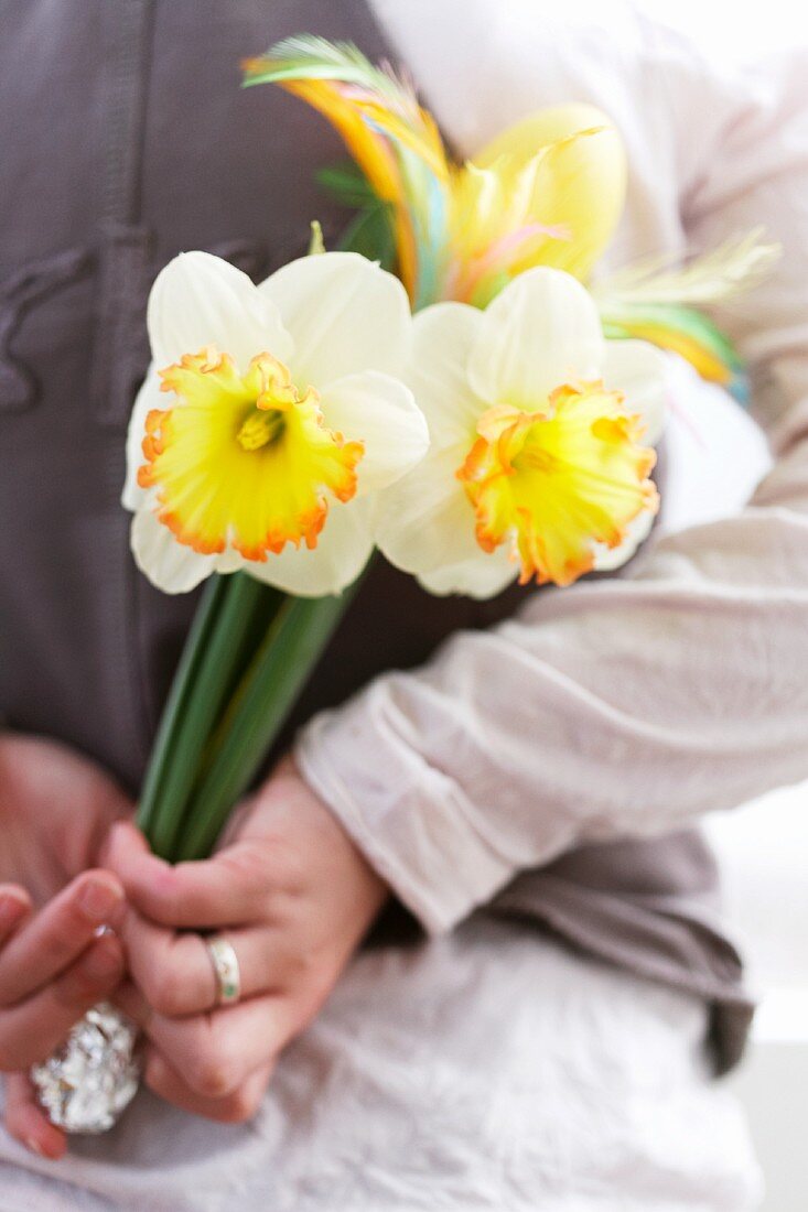 Lady holding an Easter bouquet with daffodils behind her back