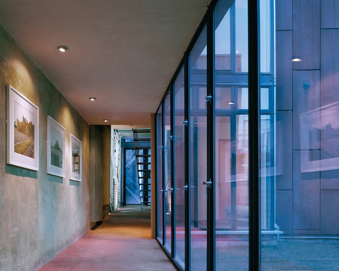 Minimalist hallway with glass facade and picture gallery on a concrete wall