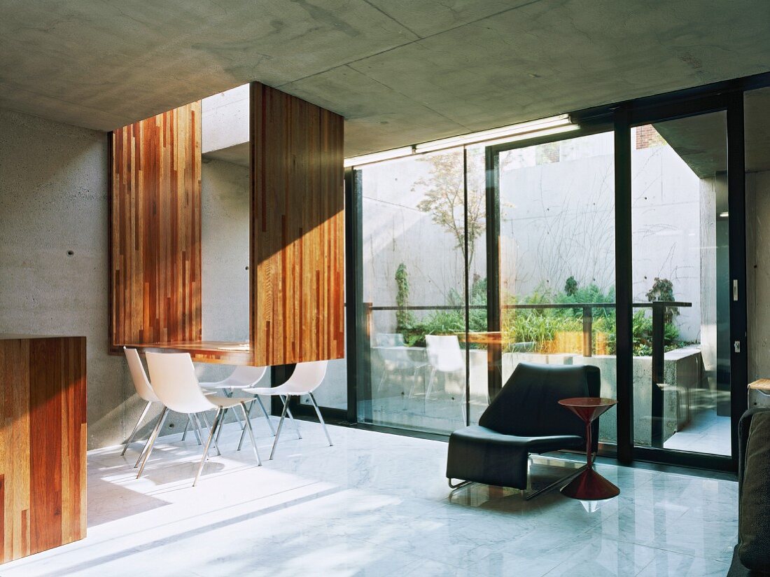 Wohnraum mit weissen Stühlen am originellen Esstisch vor Fensterfront