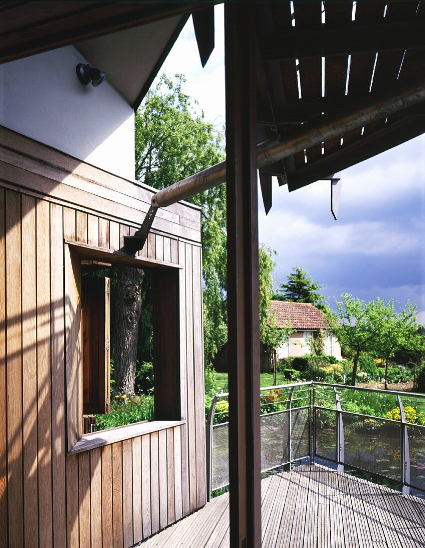 Ausschnitt eines Wohnhauses mit Holzterrasse und Gartenblick