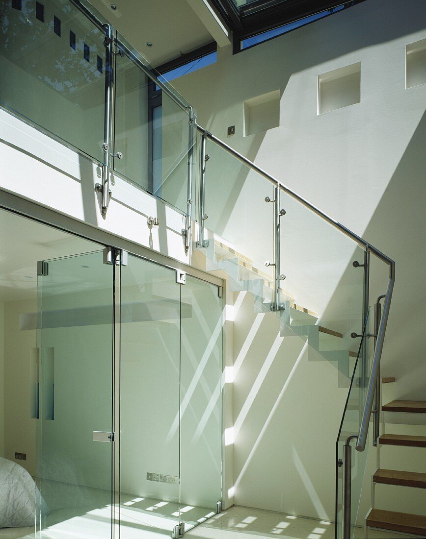 Offenes Treppenhaus mit Glasschiebetüren und Treppe mit Geländer aus Glas