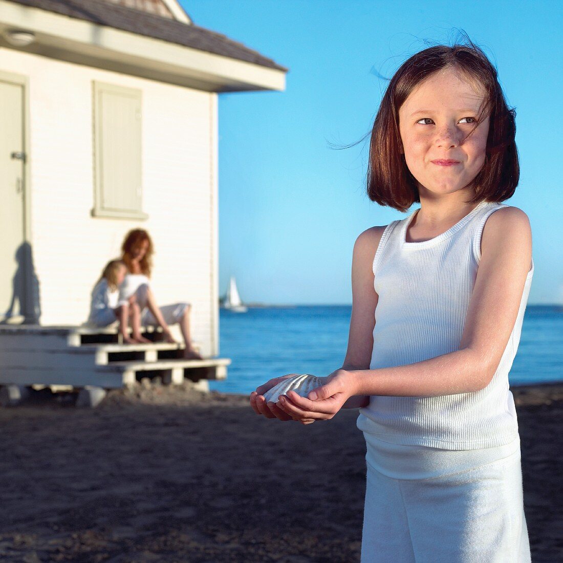 Fröhliches Mädchen am Strand, eine Muschel haltend