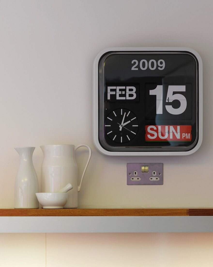Modern wall clock beside assorted ceramic pitchers on a surface