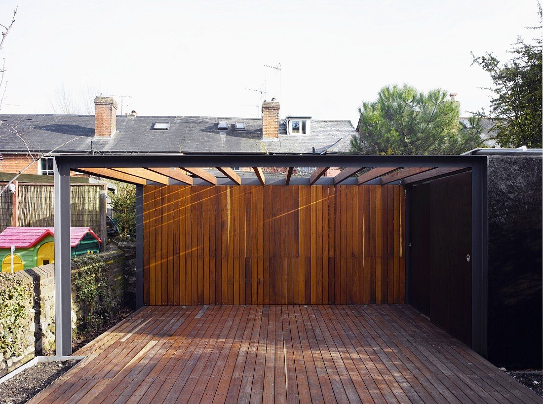 Pergola above a contemporary wood patio going over a wall