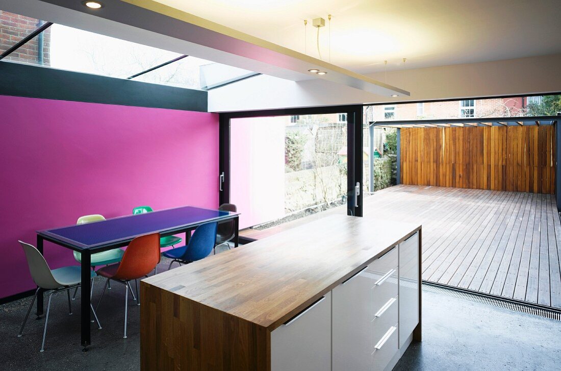 Offener Wohnraum mit freistehendem Küchenblock vor Essplatz und grossflächigem Terrassenfenster