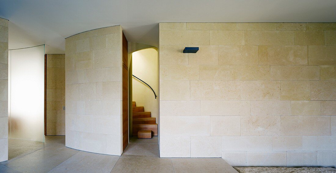Puristischer moderner Vorraum mit Steinfliesen an Wand und raumhohem Durchgang mit Blick auf Treppe