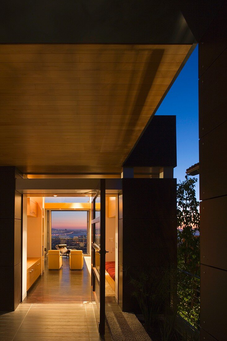 Abendstimmung auf Terrasse in zeitgenössischer Architektur mit offener Tür und Blick auf Sessel