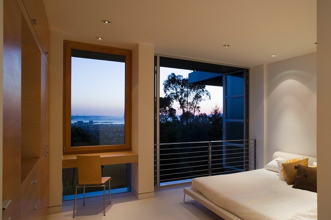 Doppelbett im zeitgenössischen Schlafraum mit offenem französischem Fenster