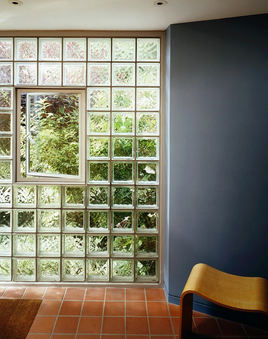Geöffnetes Fenster in Glasbausteinwand und Terrakottaboden im Vorraum