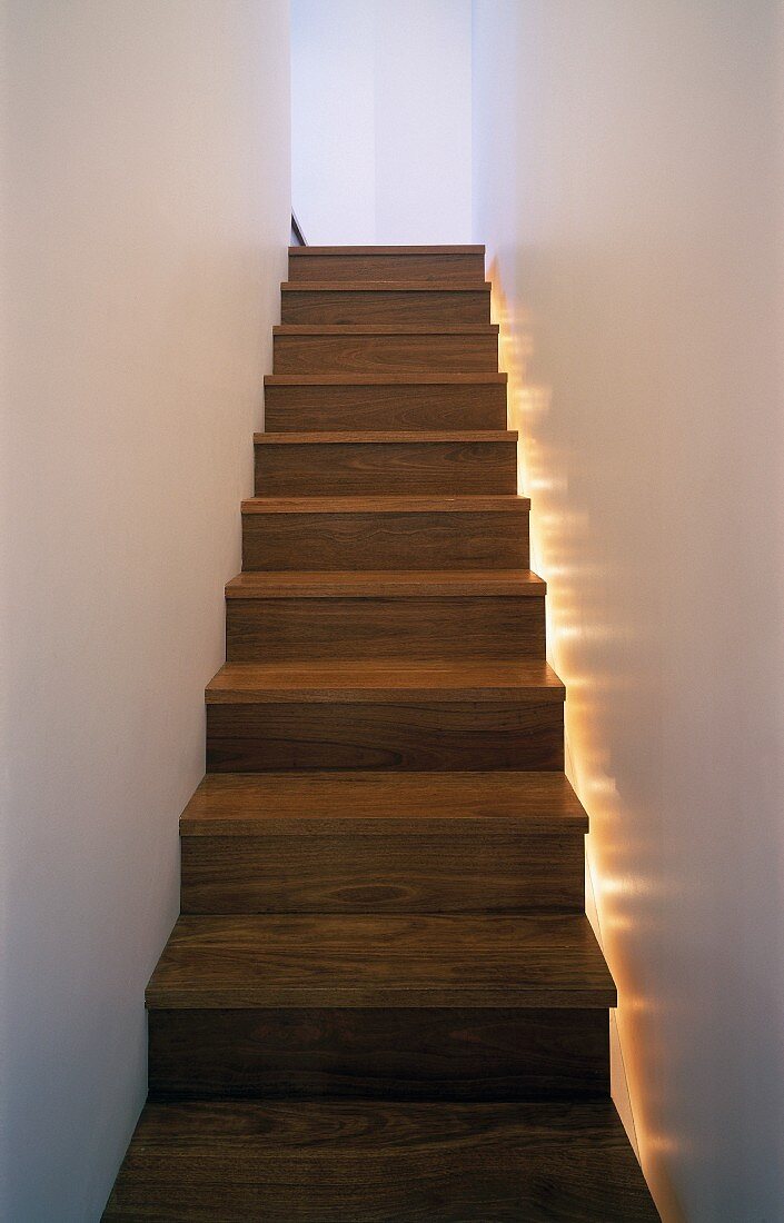 Holztreppe mit seitlicher Bodenbeleuchtung im schmalen Treppenhaus