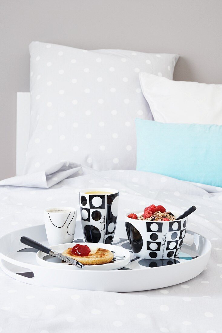 Muesli, toast with jam, coffee and orange juice on a breakfast tray on a bed