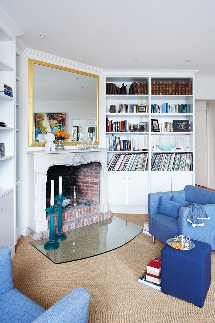 View into a living room with blue furniture, book shelve and fireplace