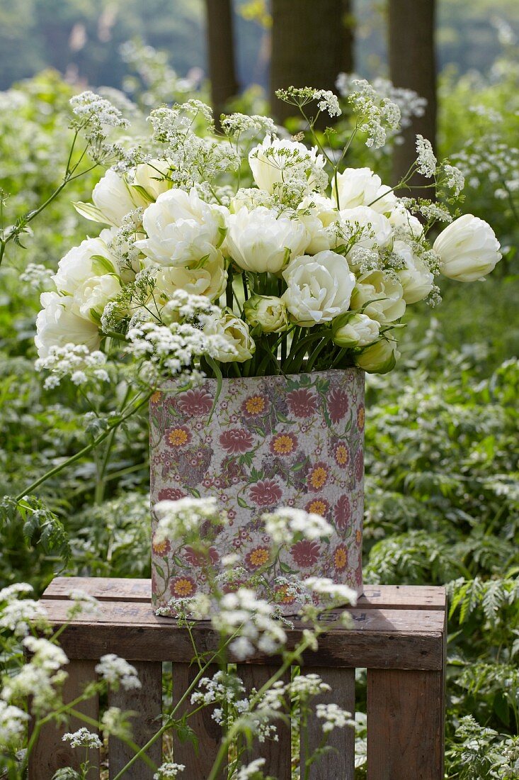 A bunch of white tulips (tulipa Maureen Double) in a vase in a garden