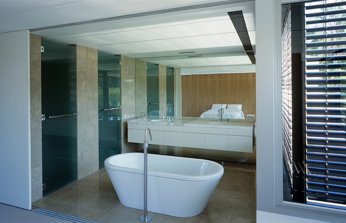 Open sliding doors and a view of a free standing bathtub fixture in front of a white vanit