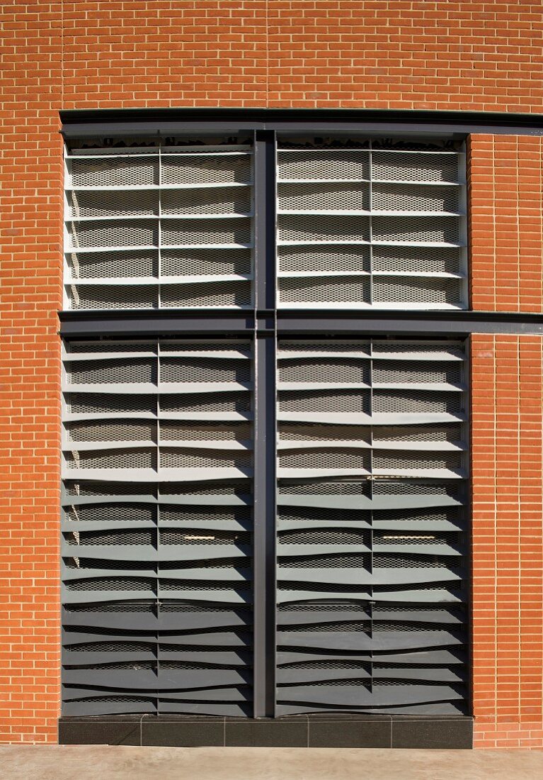Raumhohes Fenster mit geschlossener Jalousie in Klinkersteinfassade eines Wohnhauses