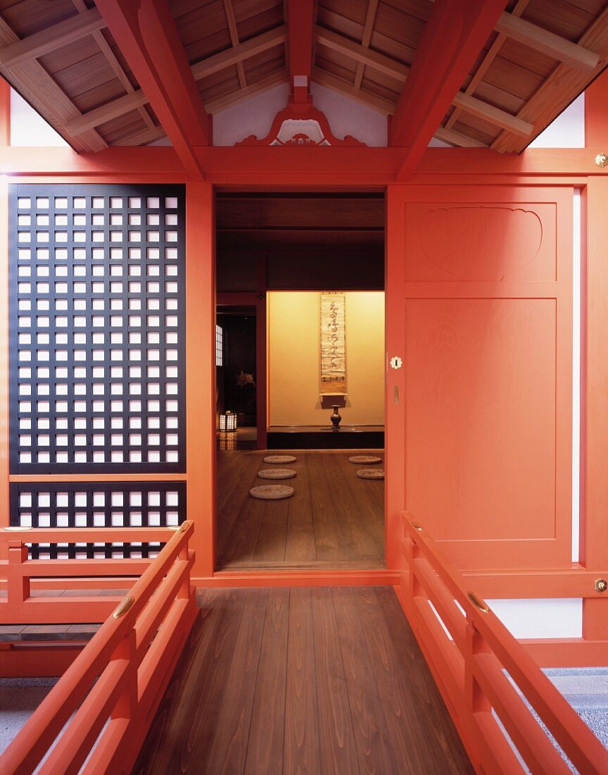 Traditionelles japanisches Wohnhaus mit hellrot lackierter Tür und Blick auf Bodenkissen