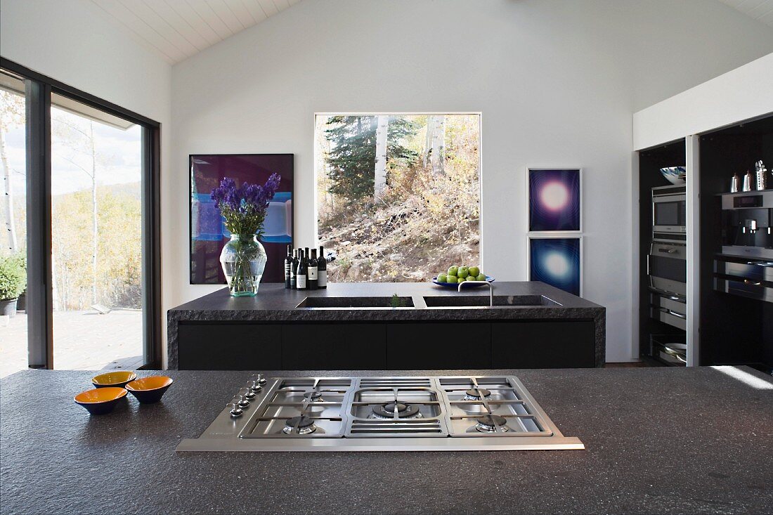 Gas stove recessed in a gray stone in front of a gray stone kitchen island in a modern kitchen