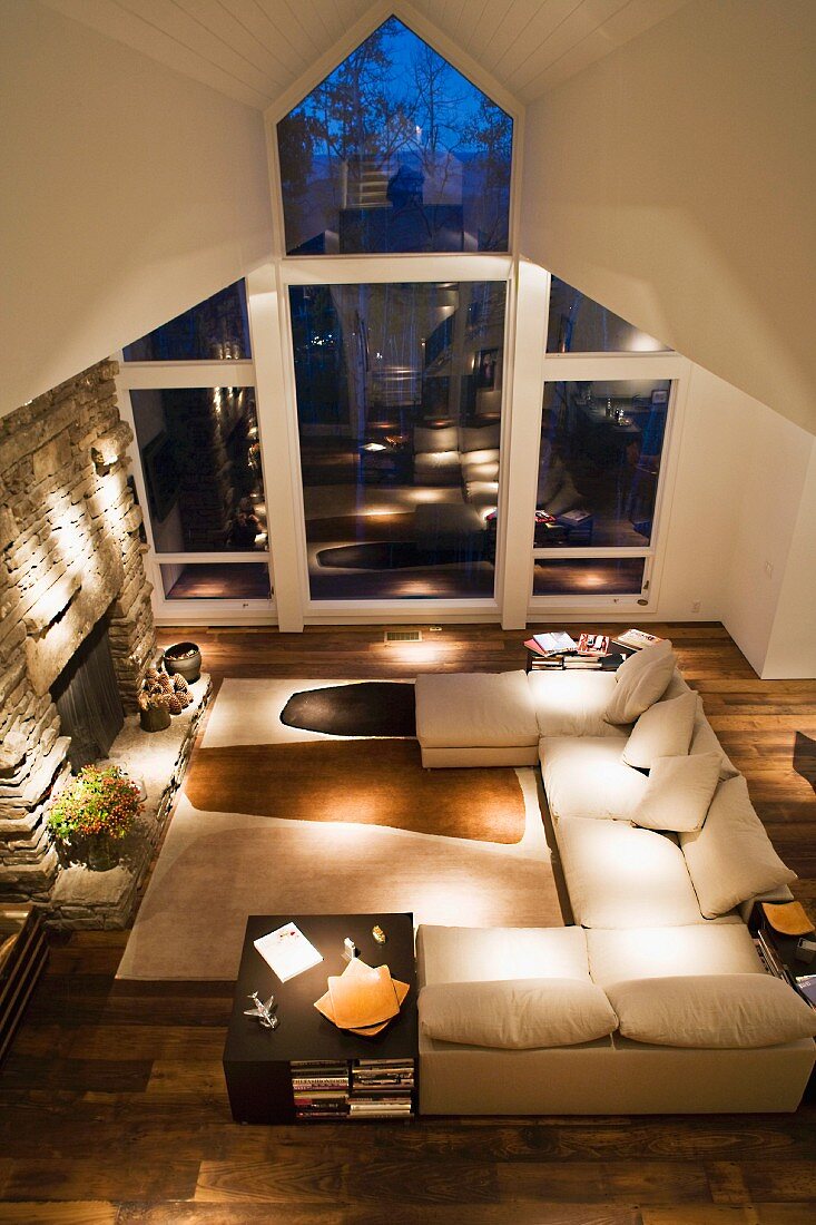 Living room suite in front of a natural stone fireplace and view through a window of the night