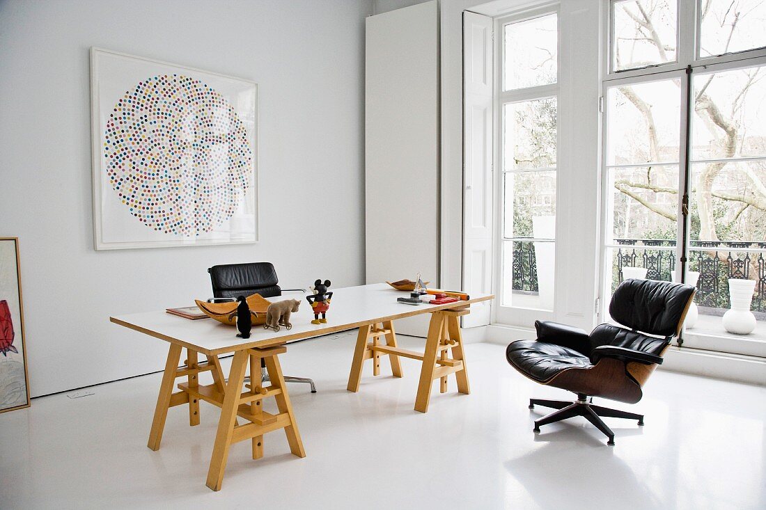 Arbeitstisch auf Holzböcken und Sessel aus Bauhauszeit im minimalistischen eleganten Raum