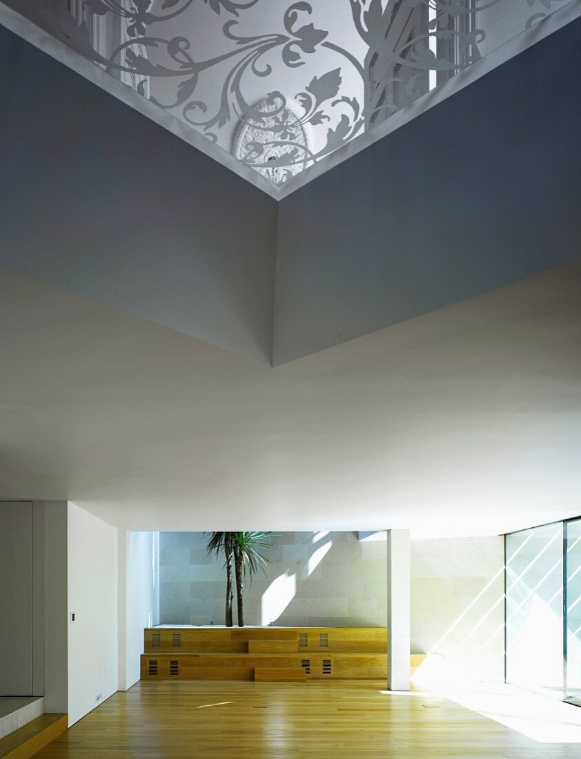 Leere Eingangshalle mit Sonnenlicht auf Parkett und Treppenstufen aus Holz in moderner Architektur