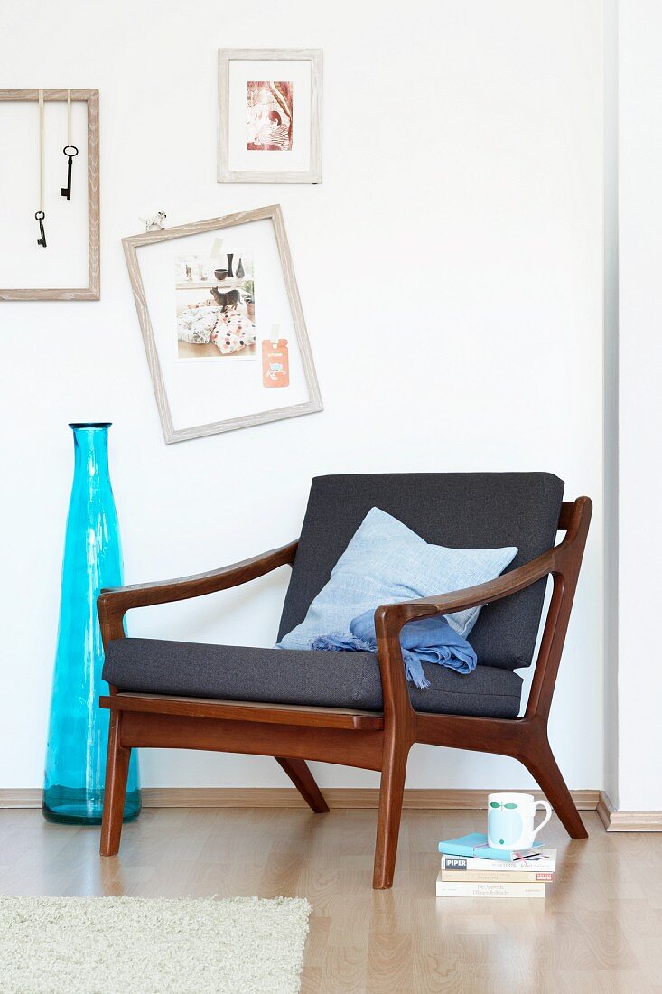 60s armchair in Danish design next to a blue floor vase and pictures on the wall