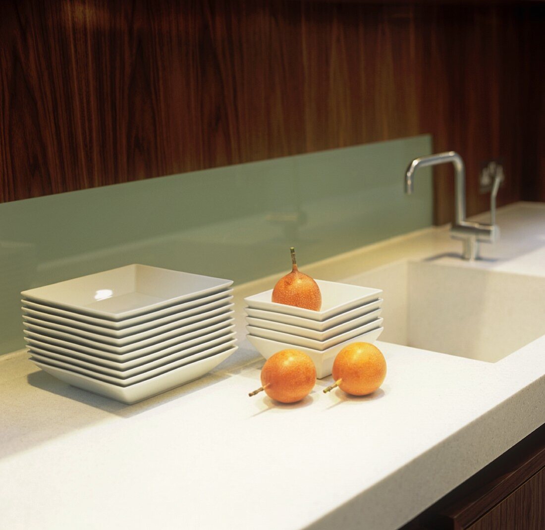 Stacks of plates and onions on a white work surface with an integrated sink