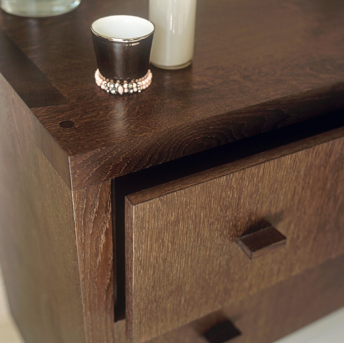 A decorative porcelain cup on a chest of drawers made of dark wood