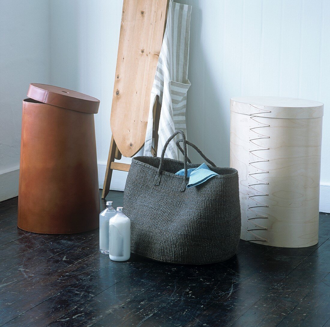 A shopping bag and coloured container in a mixture of materials and styles in front of an old fashioned ironing board