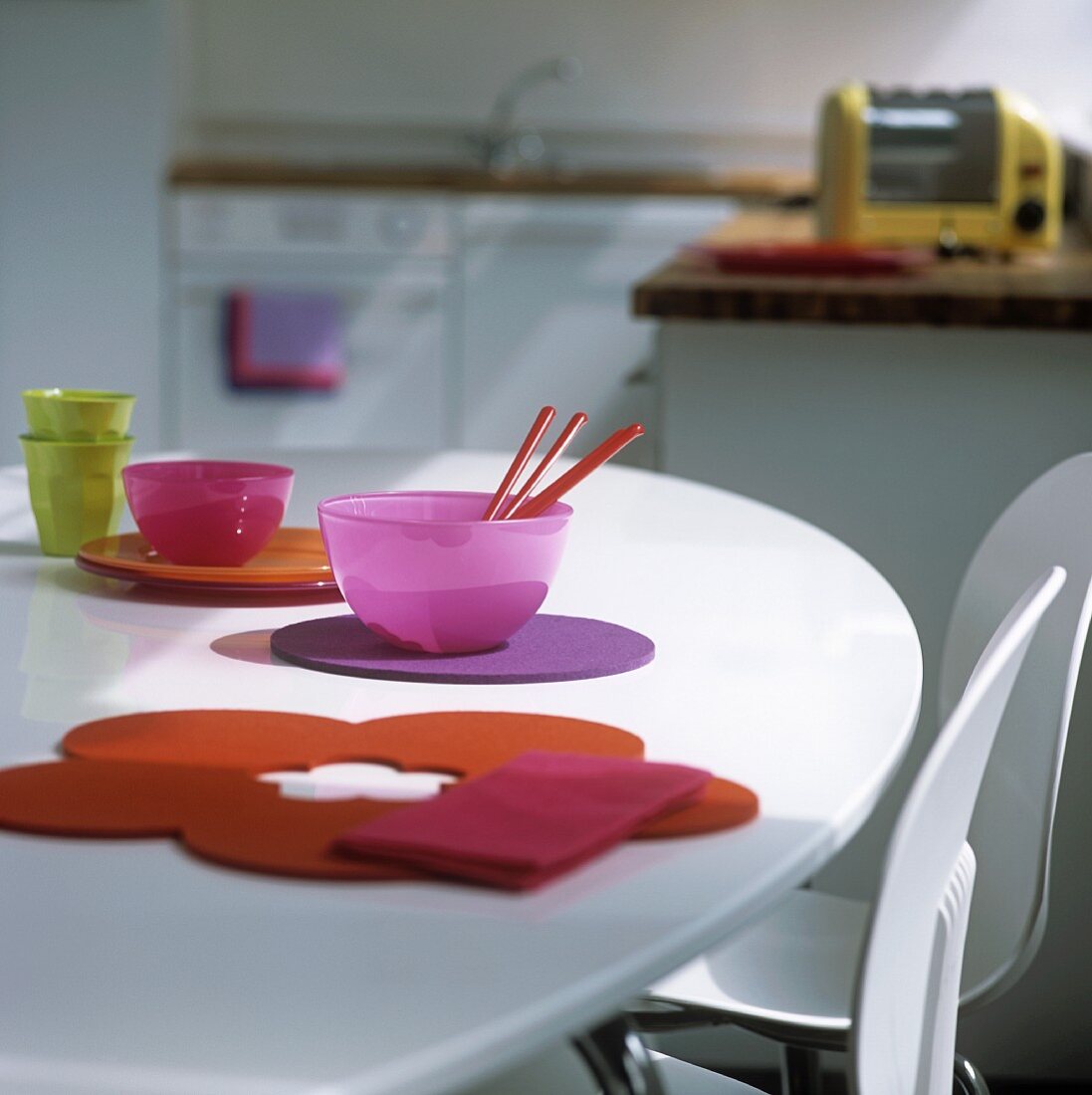 Farbige Glasschalen und Filzauflagen auf weißem Tisch