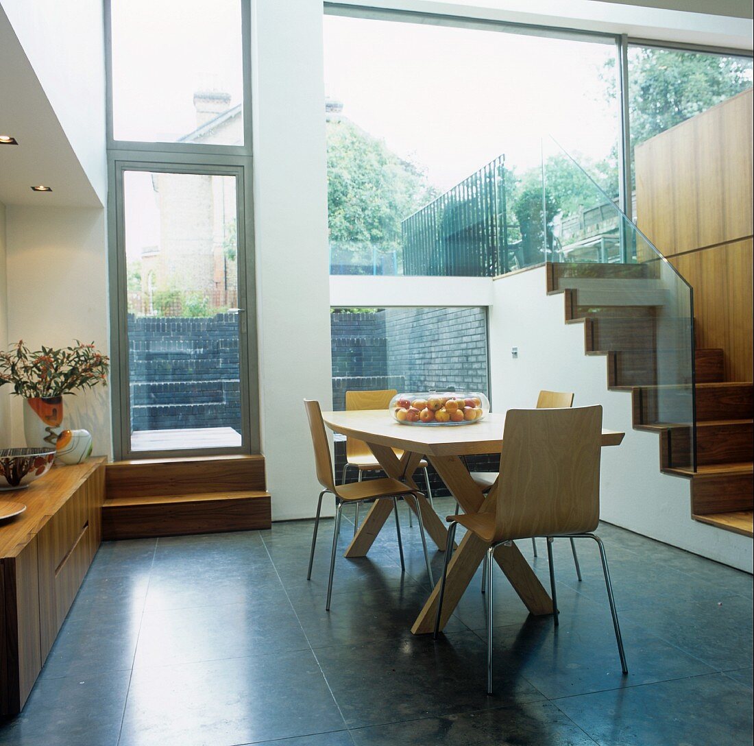 A modern, split-level house - wooden bucket chairs in an open-plan dining room with a terrace
