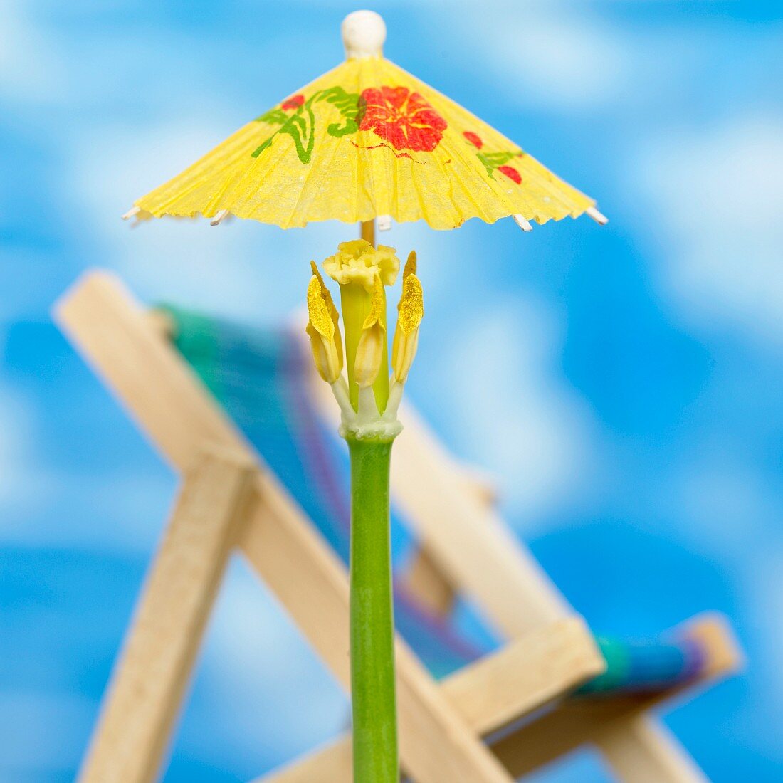A cocktail umbrella stuck into a tulip stem with a deckchair in the background