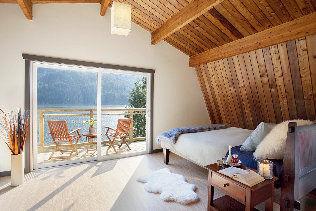 Gemütliches Schlafzimmer unter dem Dach mit Blick auf einen ruhig liegenden See (Vancouver, Kanada)