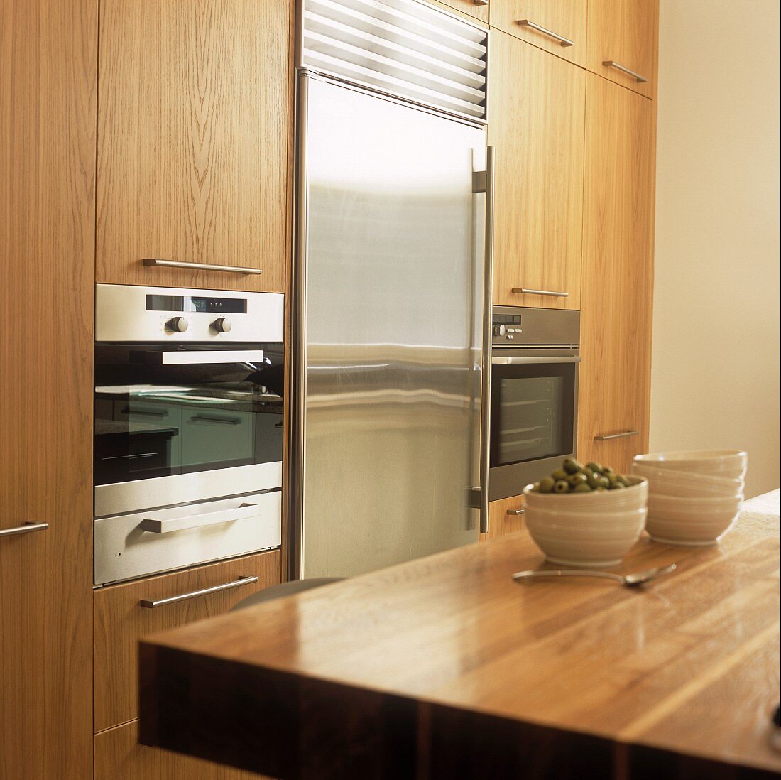 A fitted kitchen with wooden cupboards and a stainless steel fridge