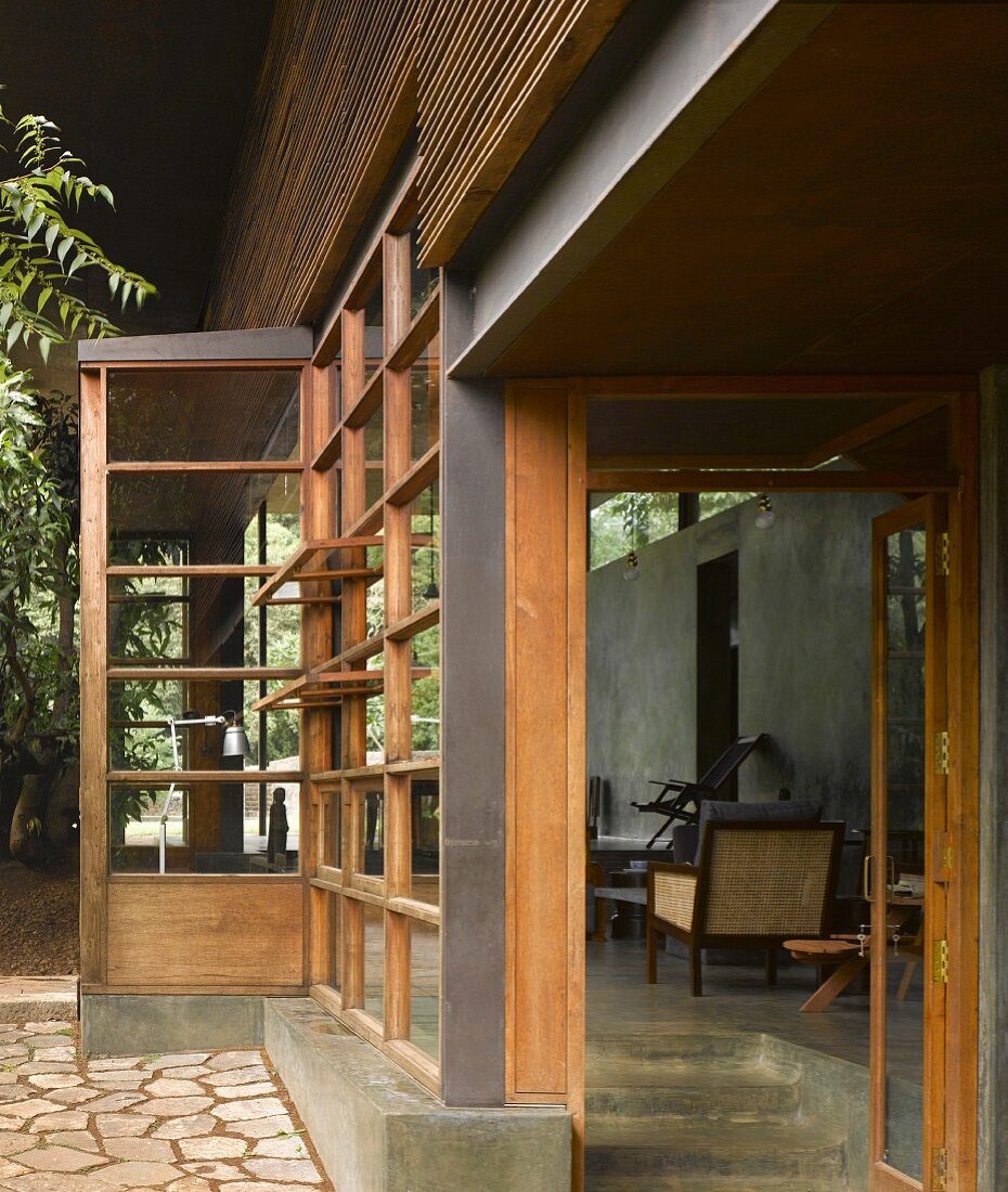Traditionelles indisches Haus mit Holzglasfassade und offener Tür mit Blick auf Veranda
