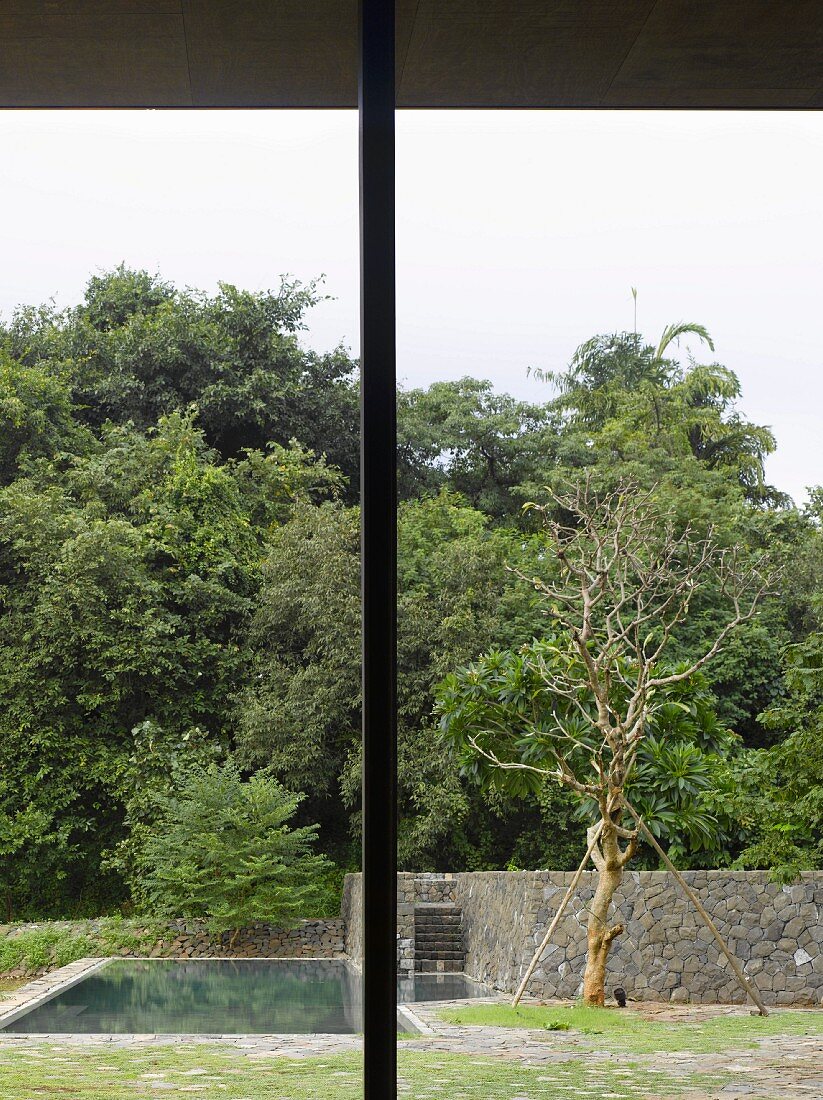 Terrassenstütze aus Metall und Blick in Garten mit Pool und Natursteinmauer