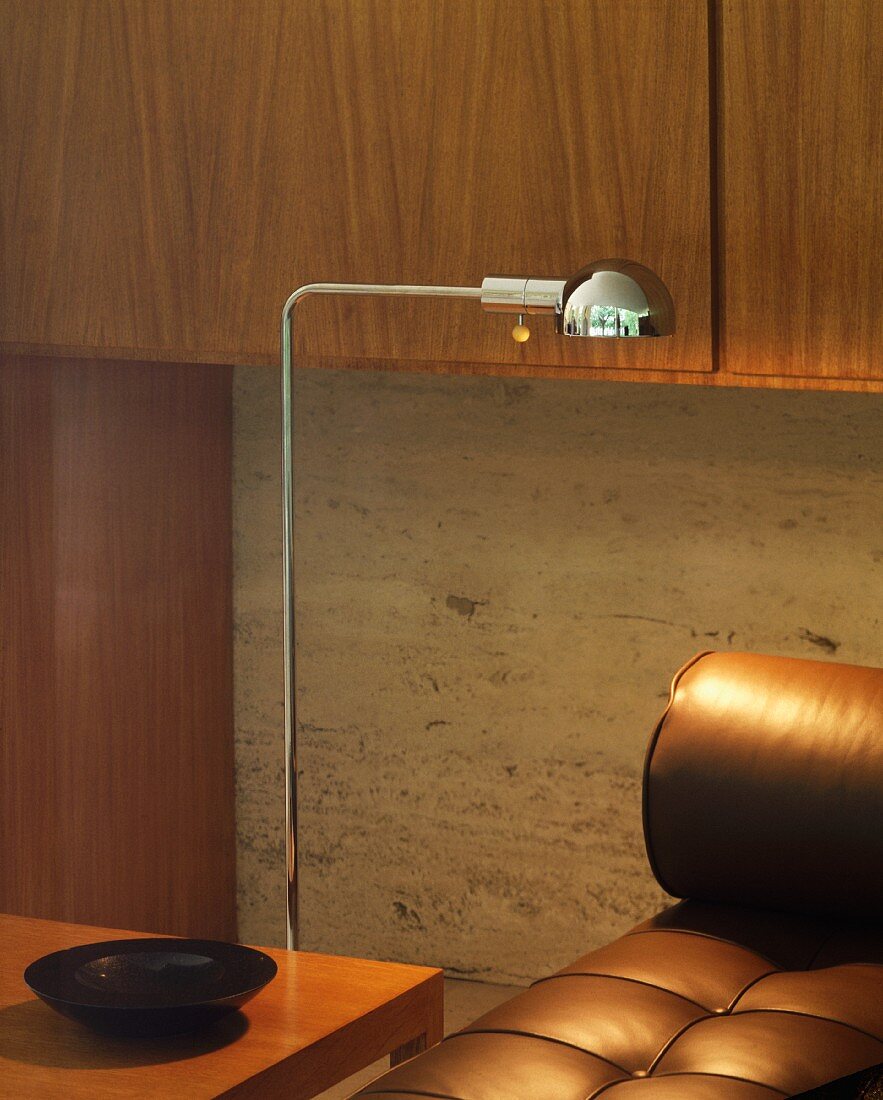 Detail of retro chrome standard lamp next to brown leather couch