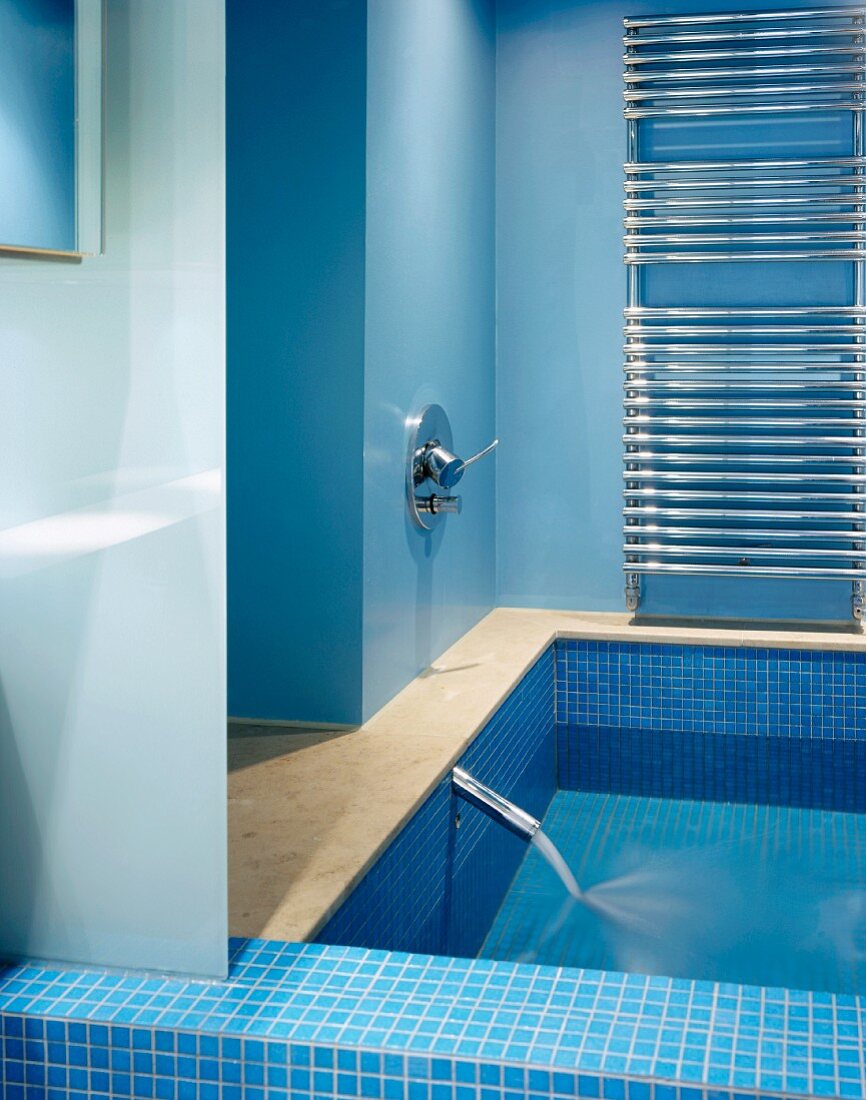 Hellblaues modernes Bad und gefüllte Badewanne mit einlaufendem Wasser
