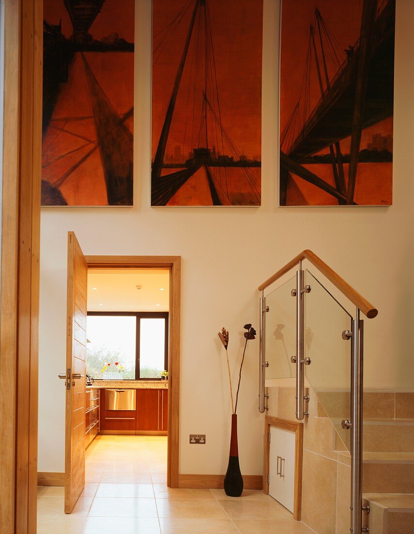A minimalistic anteroom with steps and a modern triptych above an open kitchen door