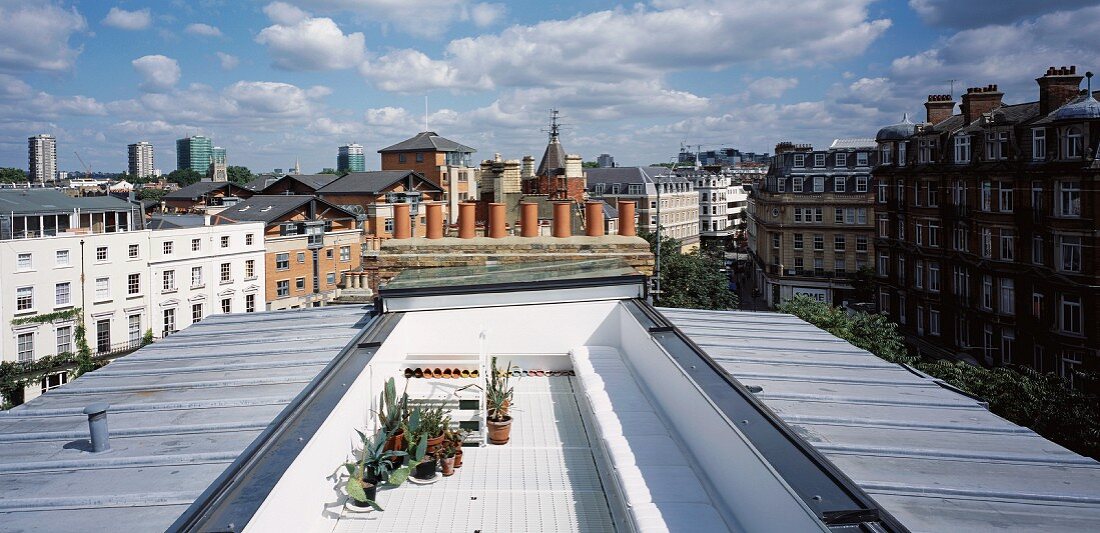 Elongate roof terrace between metal roofs with view of an English cityscape