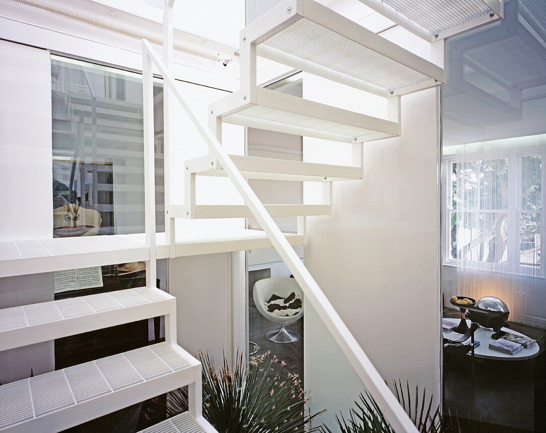 White stairwell with view into modern living room with sphere-shaped chair